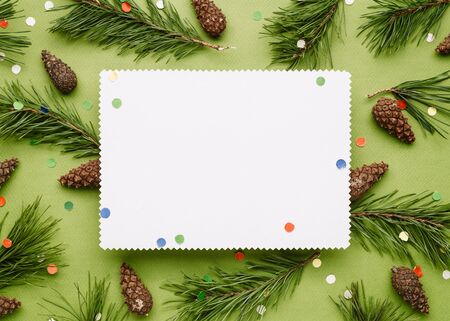 Christmas background with decor of pine branches and festive confetti. White sheet with a copy space for Christmas creep の写真素材