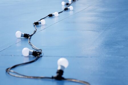Abstract blue background with a garland of light bulbs on a wire