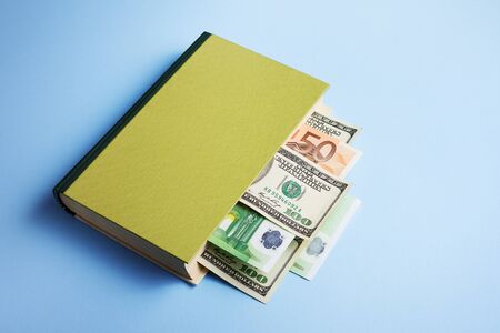 Concept of financial literacy and money management. Book with a bookmark in the form of a dollar and euro billの写真素材