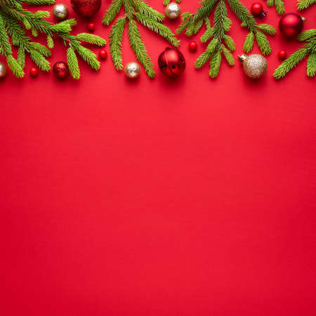 Square christmas card with fir decorations on red background / Blank with copy space for advertising text. Top view, flat layの写真素材