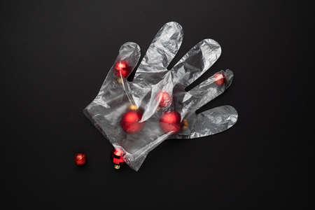 Christmas lockdown concept. Christmas balls in a protective glove on a black background. Celebrating...