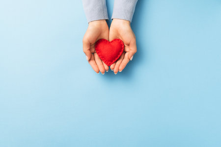 Valentines day concept with a red heart in a handful of a woman on a blue background with copy spaceの写真素材