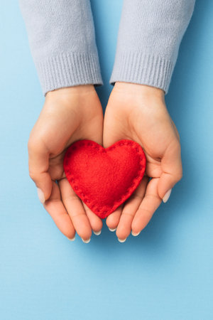 Red heart on woman palms against blueの写真素材