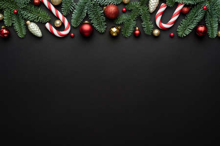 Black background with holiday border, Christmas balls, and a candy cane for Christmas design. Flat lay, top view and copy space for textの写真素材