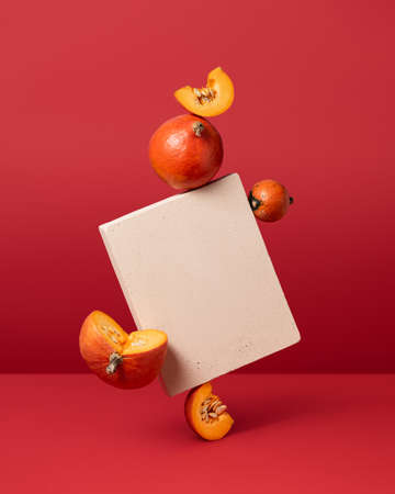 Halloween background with levitating pumpkins on red background. Conceptual still life with balancing objectsの写真素材