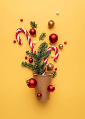 Christmas card with candy cane, Christmas balls, and fir tree branches on yellow backgroundの写真素材
