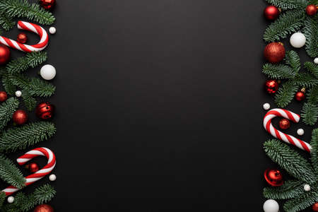 Frame made of Christmas decorations fir branches, candy cane and Christmas balls on a black backgroundの写真素材