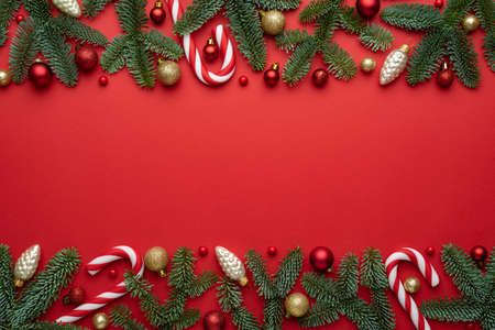 Red Merry Christmas and New Year background. A decorative border of fir branches, gifts, Christmas balls and candy cane. Christmas creepの写真素材