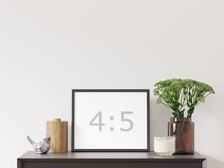Empty horizontal frame 4: 5 on white wall with black dresser, green plant in brown glass vase and decor - close up image.の写真素材