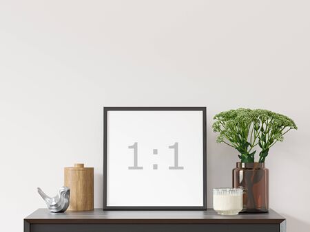 Empty square frame on white wall with black dresser, green plant in brown glass vase and decor - close up image.の写真素材