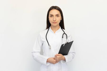 Friendly female doctor holding a folder in her hands, a stethoscope on her neckの写真素材