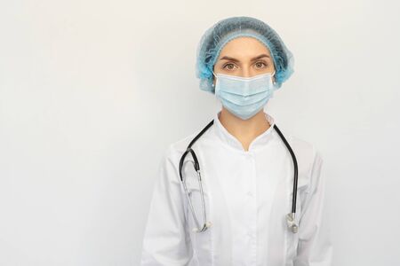 A doctor in a protective medical mask with a stethoscope in his handsの写真素材