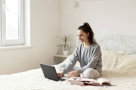 Young girl woman on the bed, distance learning for students. Coronavirus. Quarantine. Woman look at...
