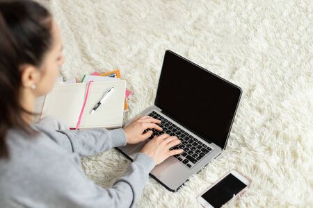 Young girl woman on the bed, distance learning for students. Coronavirus. Quarantine. Woman look at a laptop computer. Freelancer, distant work, work at home, online educationの写真素材
