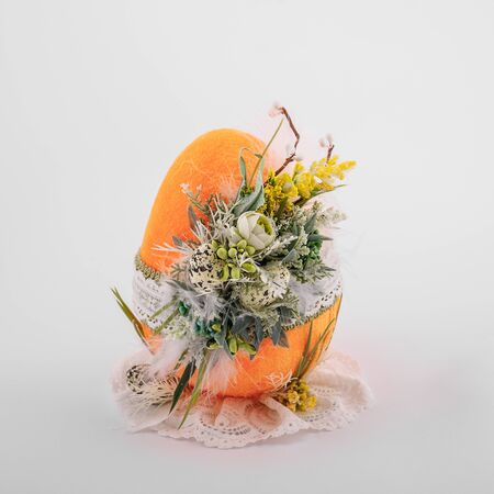 handmade decorative Easter orange egg on a white background with ornaments textile and flowersの写真素材