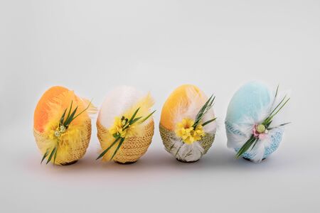 handmade decorative easter eggs on a white background with textile and flower ornamentsの写真素材