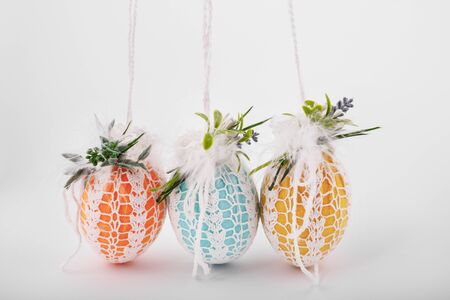handmade decorative easter eggs on a white background with textile and flower ornamentsの写真素材
