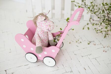 pink wooden baby stroller for toys, pink horse, spring background,の写真素材