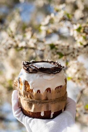Easter cake and colored eggs on a plate, white gloves, a festive composition in a rustic style,...