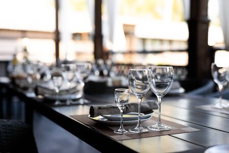 Festive table setting with empty wineglasses. Selebration banquet with brown napkins, plates and wineglasses for white and red wine on the wooden tableの写真素材