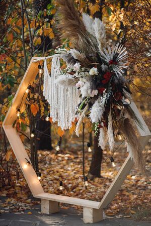 Wedding ceremony with arch in rustic style with macrame. Wedding exit ceremony with wood arch with fresh flowers and pampass grassの写真素材