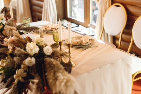 The presidium of the newlyweds at the wedding. Table for the bride and groom with fresh flowers pampass grass and candles in restaurant. Banquet table for newlyweds. Close upの写真素材