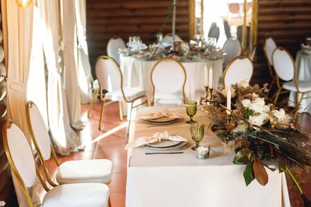 Presidium table setting with green wineglasses and candles. Side view selebration banquet with plates and wineglasses for white and red wine on the white table in restaurantの写真素材