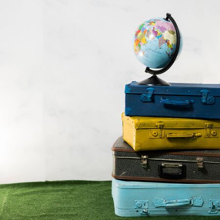 Travel or turism concept. Isolated globe on four vintage blue yellow brown suitcasesの写真素材