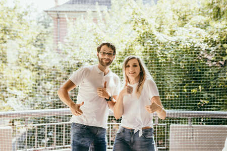Happy couple standing together and show ok. Lovely family on balcony at home with nature background