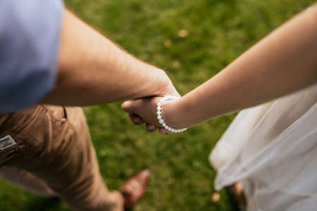Romantic couple holding hands standing on green grass. Idylic loving family in love