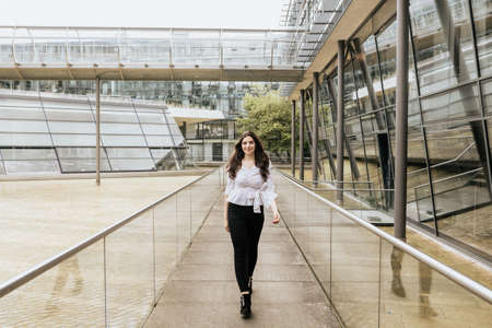 Beautiful attractive woman wearing white blouse and black pants indoor. Young woman on building backgroundの写真素材
