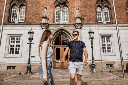 Horizontal photo of romantic couple stand hold hands and look to each other. Happy man and woman on...