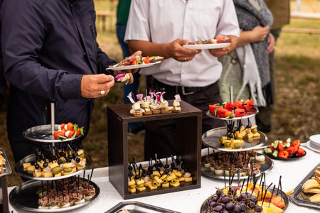 A set of canapes and snack at a banquet with white table. Slices of tomato, olive, cheese, bread and...