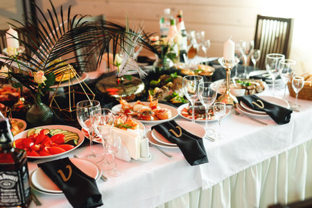Festive table setting with wine glasses, food and fresh fern. Selebration banquet in white black colorsの写真素材