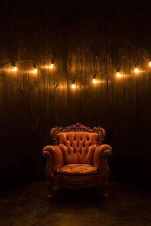 Modern brown armchair with garlands. Vintage armchair on dark wood backgroundの写真素材