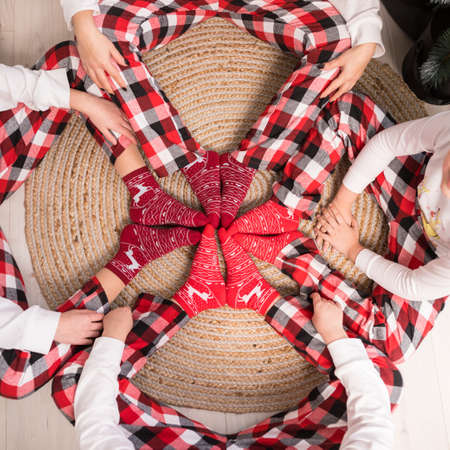 Close up of families legs with Christmas socks and hands in square in home interior. Concept of Christmas and New Yearの写真素材