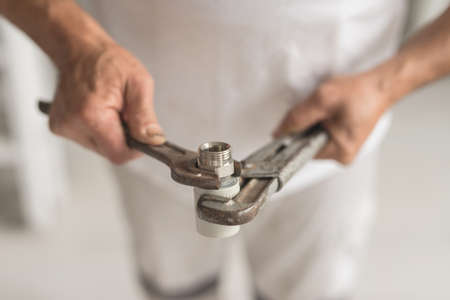 Man take two keys wrench and balloon in hands. Close up of hands with instryment for heating system...