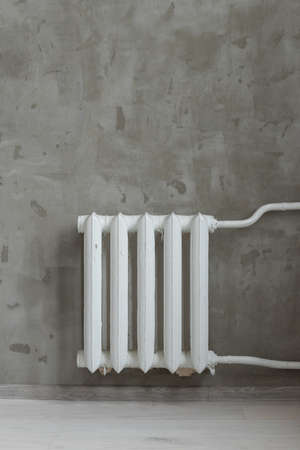 Heating battery on the gray wall. Vertical photo of white metal heaterの写真素材