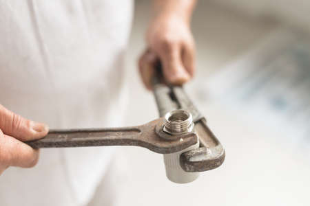 Side view of two keys wrench and balloon in hands. Close up of hands with instryment for heating system in warm colorsの写真素材