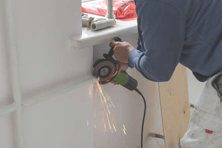 Man cuts a pipe with a grinder sparks fly. Close-up of working process with Grinding machine