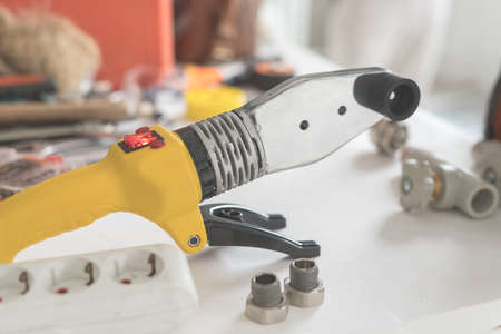 Soldering iron for polypropylene on white table. Close-up of yellow iron for heating or water supply