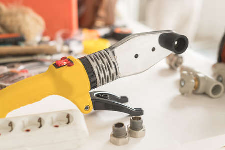 Soldering iron for polypropylene on white table. Close-up of yellow iron for heating or water supplyの写真素材
