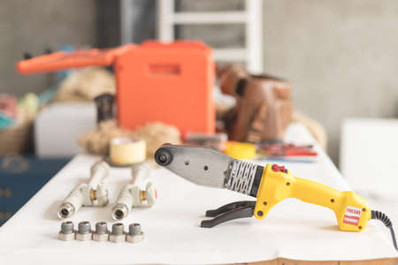 Soldering iron for polypropylene on white table. Side view of yellow iron for heating or water supplyの写真素材