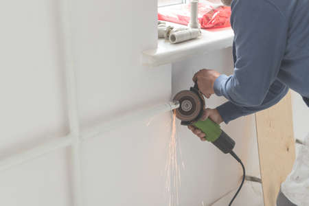 Man cuts a pipe with a grinder sparks fly. Side view of working process with Grinding machineの写真素材