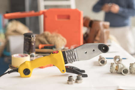 Soldering iron for polypropylene on white table. Side view of yellow iron for heating or water supplyの写真素材