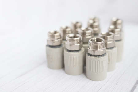 Combined couplings for connecting metal and polypropylene water pipes. Side view of nuts in warm colorsの写真素材