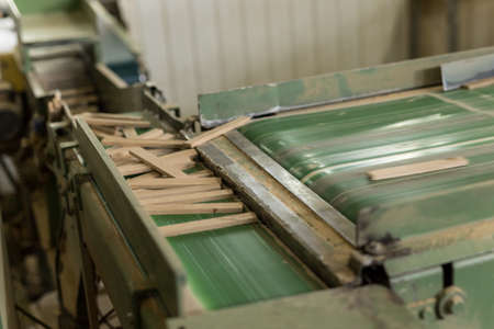 The close up of decorative not chipped wooden blocks in green cutting machine. Concept of paneling...