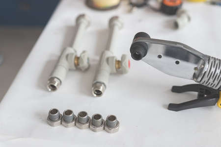 Soldering iron for polypropylene with polypropylene pipe with tap on white tableの写真素材