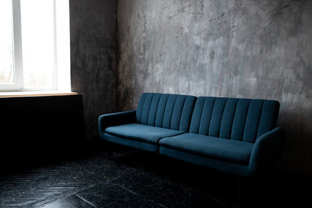 blue sofa in the interior of a room with a concrete wall.