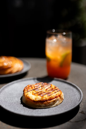 Fried cheese pancakes on a black plate with a glass of orange juiceの写真素材